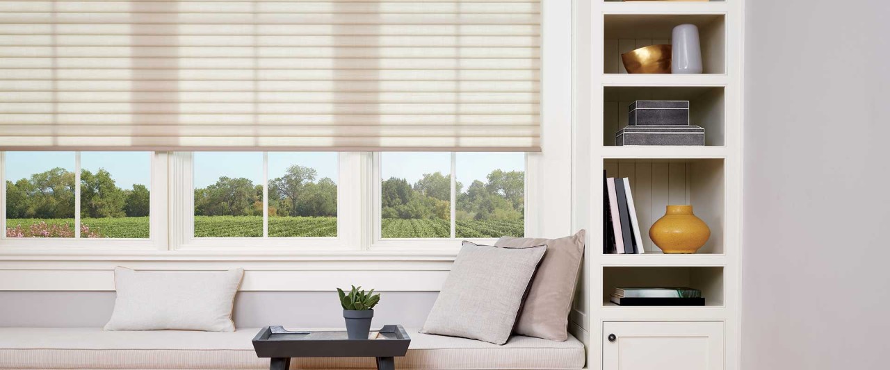 Window seat with pillows, bookshelf, and Sonnette cellular shades.